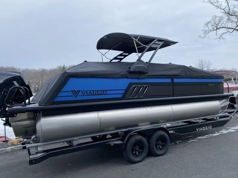 Slide: The Image of 2025 Viaggio D24U pontoon boat with blue and black design on a trailer. - 19