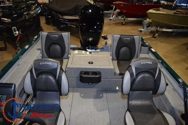 Slide: The Image of 2025 Lund 1675 Adventure Sport boat interior with four seats and motor in showroom. - 16