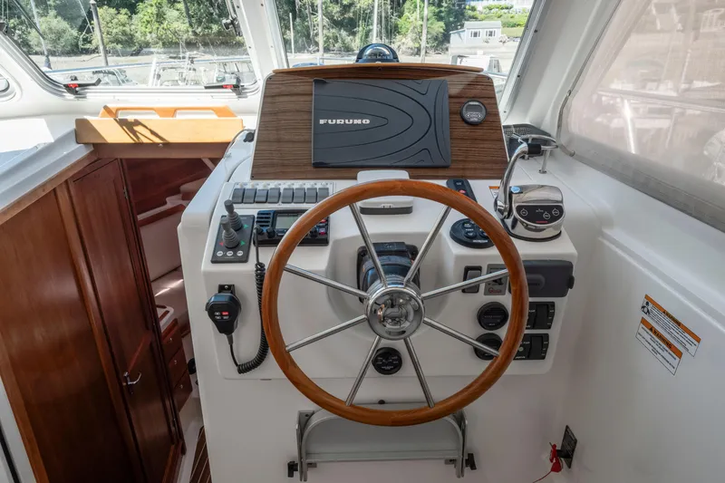 Slide: The Image of Helm of 2016 Back Cove 30 boat with wooden steering wheel and navigation controls. - 14