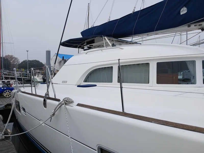 Slide: The Image of 2007 Lagoon 380 S2 catamaran docked at a marina, featuring sleek white design. - 10