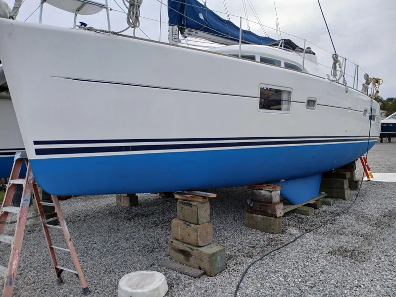 Slide: The Image of 2007 Lagoon 380 S2 catamaran on blocks, white and blue hull, outdoor setting. - 19