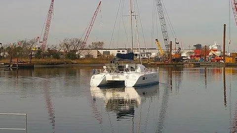 Slide: The Image of 2007 Lagoon 380 S2 catamaran docked in an industrial harbor setting. - 2