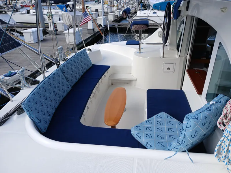 Slide: The Image of 2007 Lagoon 380 S2 yacht cockpit with blue cushioned seating and wooden table. - 23
