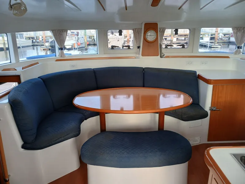 Slide: The Image of Interior of 2007 Lagoon 380 S2 catamaran with curved seating and wooden table. - 28