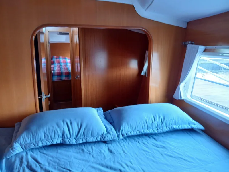 Slide: The Image of Interior cabin of 2007 Lagoon 380 S2 catamaran with blue bedding and wooden finish. - 29