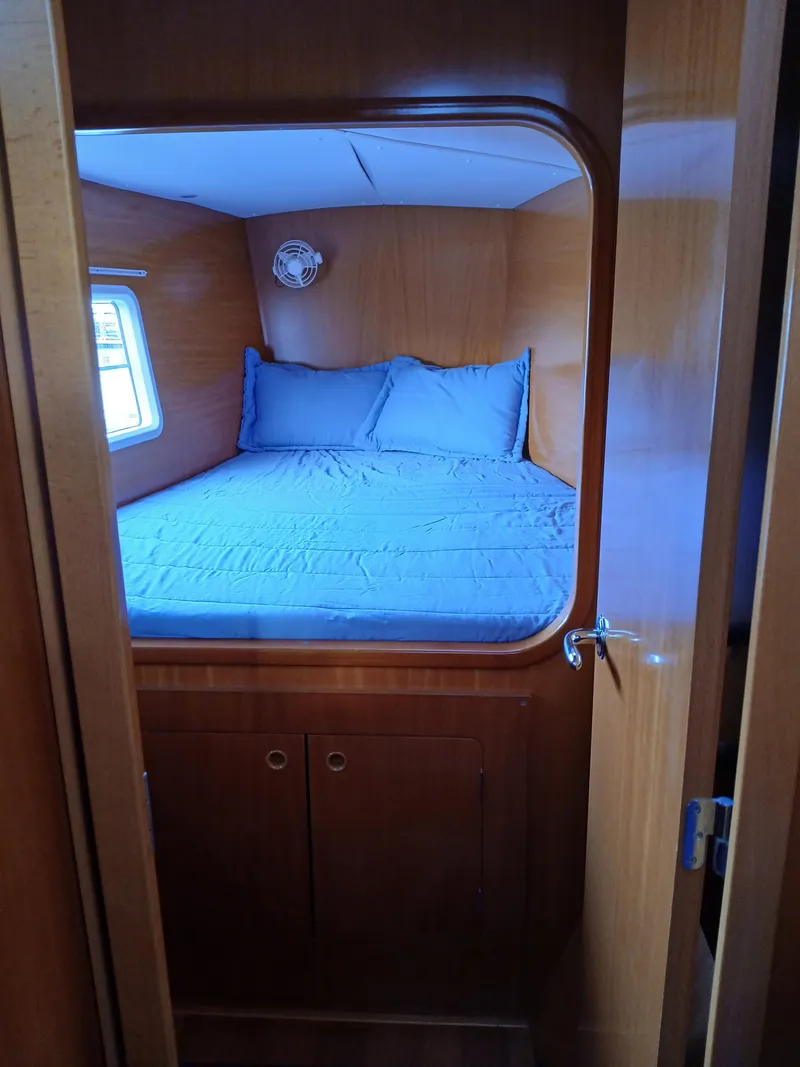 Slide: The Image of Cozy cabin interior of 2007 Lagoon 380 S2 catamaran with bed and wooden finish. - 32