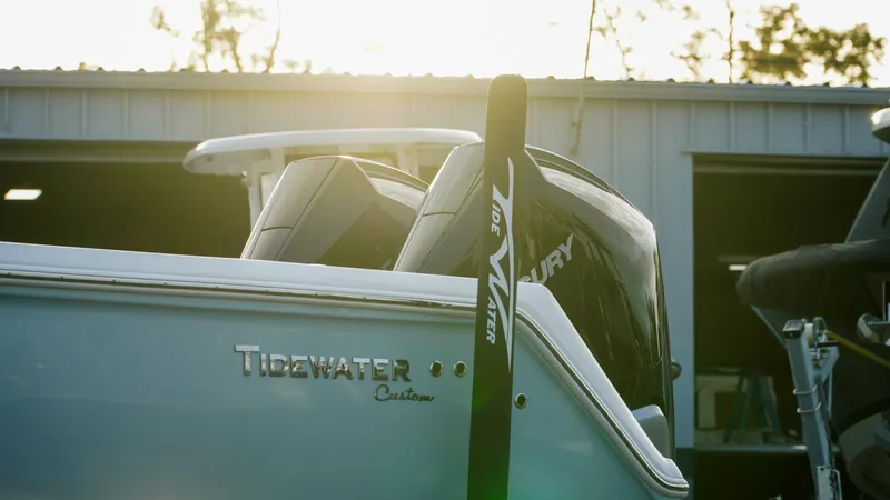 Slide: The Image of 2023 Tidewater 320 CC Adventure boat with Mercury engine, docked near a warehouse. - 13