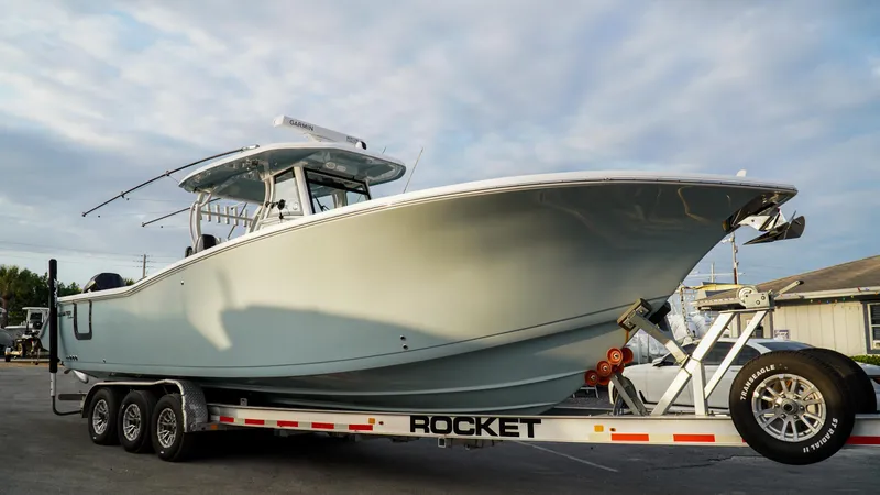 Slide: The Image of 2023 Tidewater 320 CC Adventure boat on a trailer under a cloudy sky. - 4