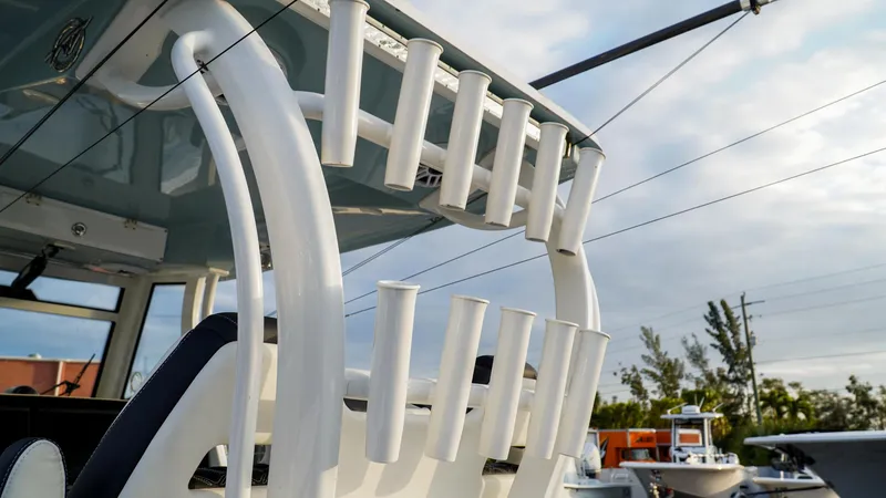 Slide: The Image of 2023 Tidewater 320 CC Adventure boat with rod holders under a cloudy sky. - 8