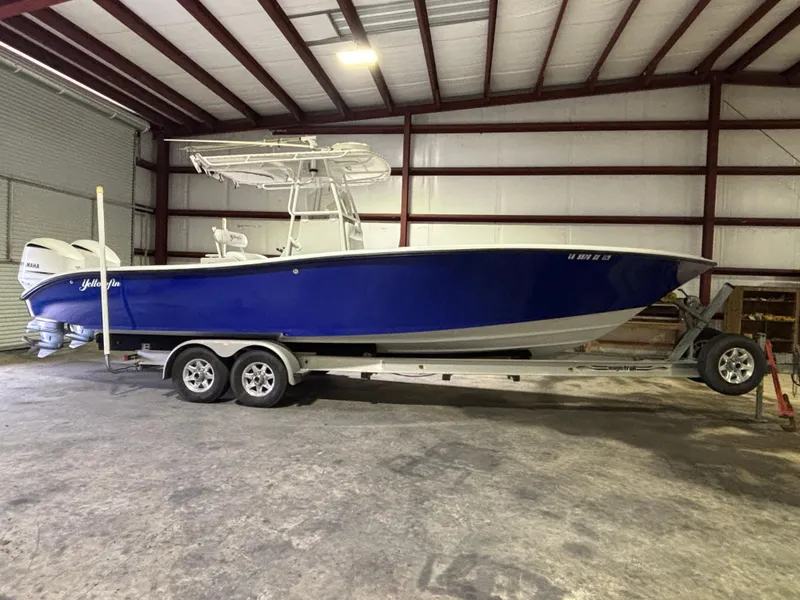 Slide: The Image of 2001 Yellowfin 31 boat in storage, blue hull, on a trailer inside a warehouse. - 0