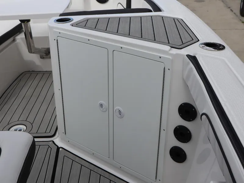 Slide: The Image of 2025 Yamaha Boats 222 FSH Sport E interior, featuring storage compartment and sleek deck design. - 24