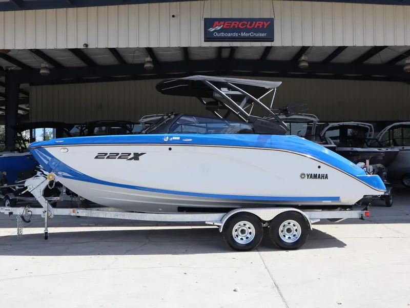 Slide: The Image of 2025 Yamaha Boats 222XD on trailer, blue and white design, parked at dealership. - 3