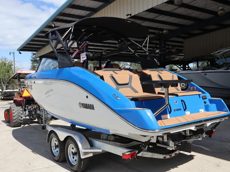 Slide: The Image of 2025 Yamaha Boats 222XD on trailer, blue and white, parked under a shelter. - 6