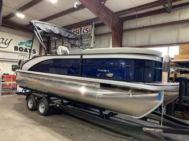Slide: The Image of 2025 Harris Cruiser 210 pontoon boat on trailer in indoor showroom. - 0