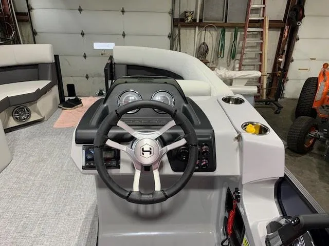 Slide: The Image of 2025 Harris Cruiser 210 boat interior with steering wheel and dashboard in a garage setting. - 3