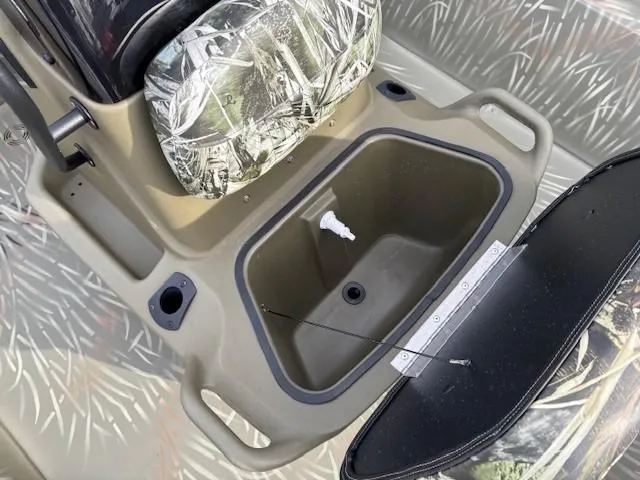 Slide: The Image of 2024 Tracker Grizzly 1860 CC boat interior with open storage compartment and camouflage seat. - 11
