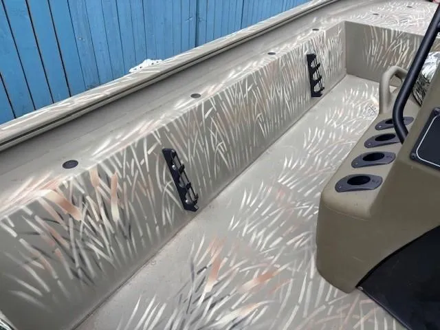 Slide: The Image of 2024 Tracker Grizzly 1860 CC boat interior with camouflage design and rod holders. - 13