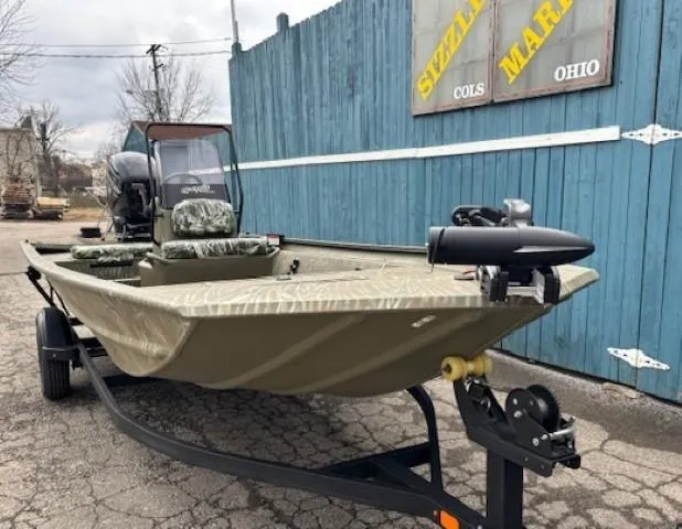 Slide: The Image of 2024 Tracker Grizzly 1860 CC boat on trailer, parked outdoors near blue fence. - 2