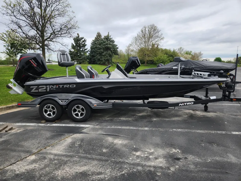Slide: The Image of 2025 Nitro Z21 XL boat on trailer in parking lot, surrounded by trees. - 1