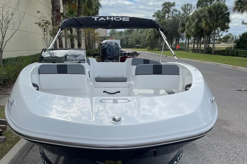 Slide: The Image of 2025 Tahoe T16 boat with sleek white design, parked outdoors. - 2