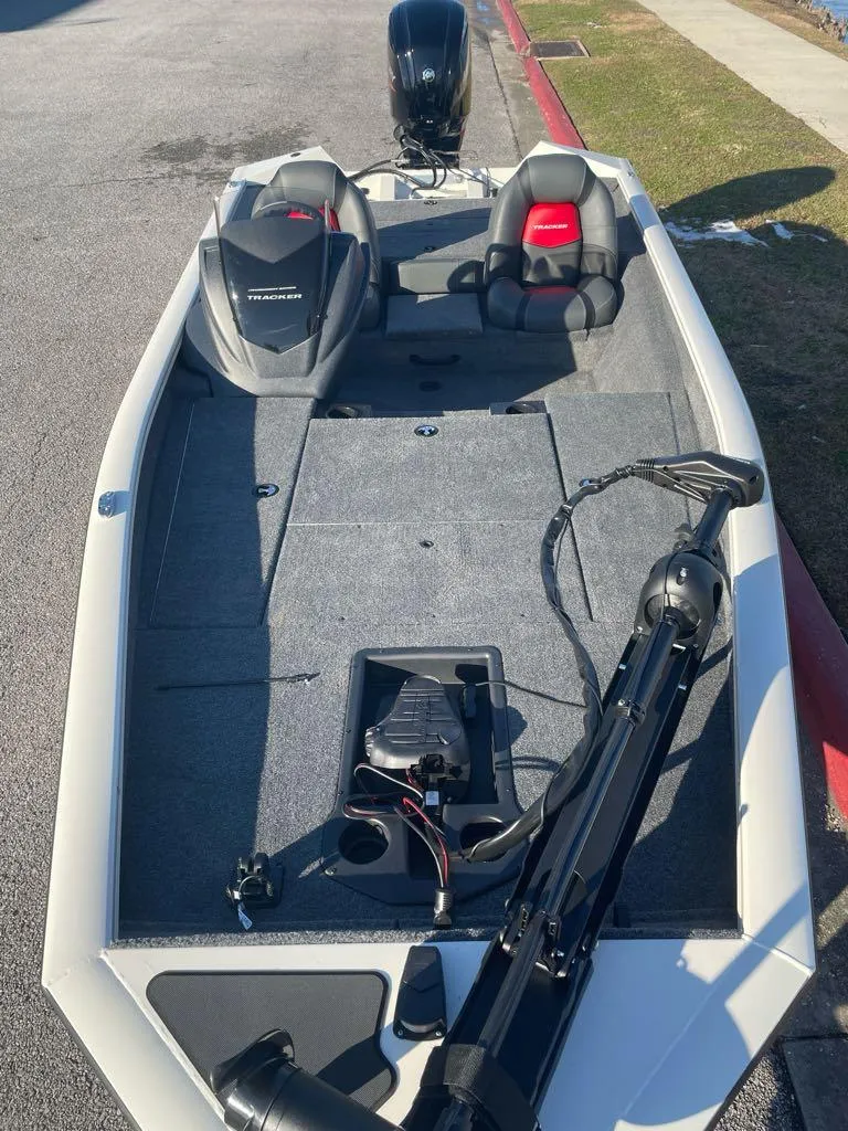 Slide: The Image of 2025 Tracker Pro Team 175 boat with seating and motor, parked on pavement. - 4