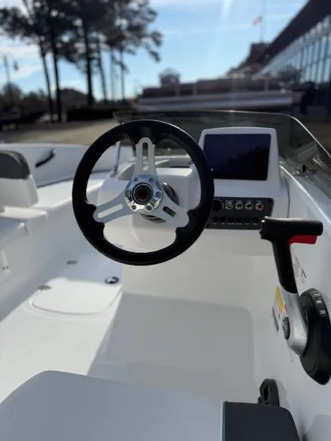 Slide: The Image of 2025 Tahoe T16 boat interior with steering wheel and control panel, docked outdoors. - 47
