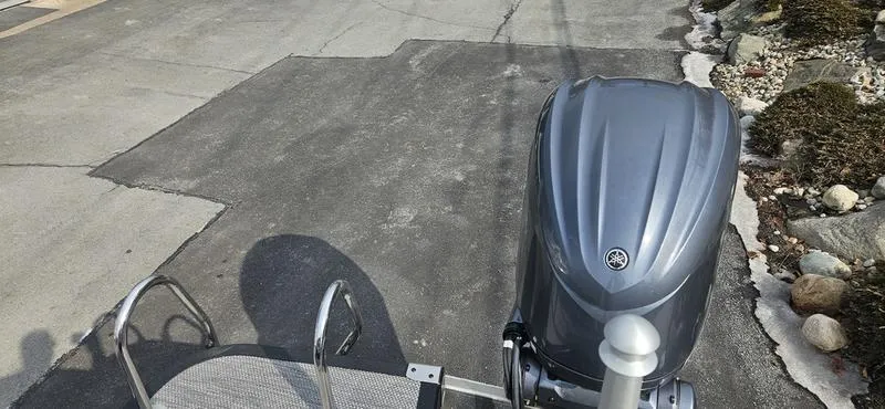 Slide: The Image of 2024 Bennington R 24 RTFBA boat with a sleek outboard motor on a paved surface. - 10