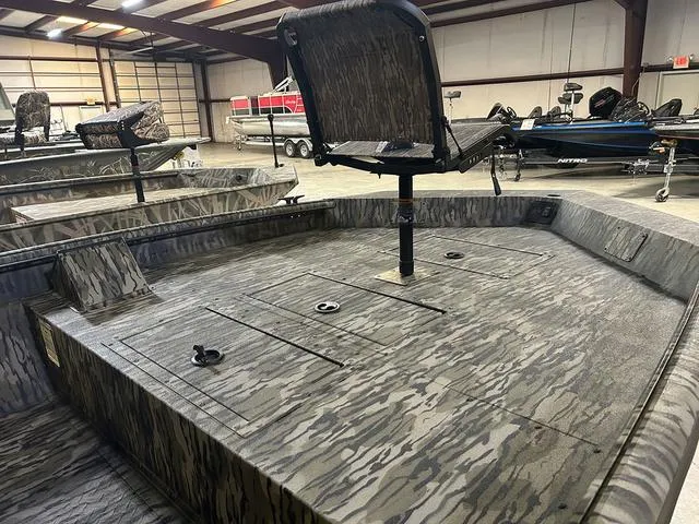 Slide: The Image of 2025 SeaArk Shadow 18 T Center Console boat interior with camo design in a warehouse. - 5