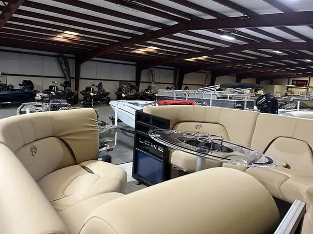 Slide: The Image of 2023 Lowe Retreat 230 RFL TLX pontoon boat interior with beige seating in showroom. - 5