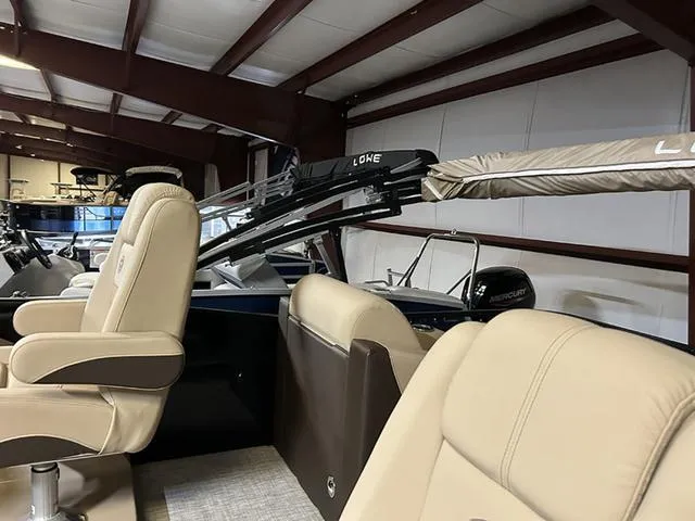 Slide: The Image of 2023 Lowe Retreat 230 RFL TLX boat interior with beige seating in a showroom. - 6