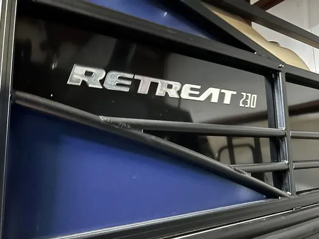Slide: The Image of 2023 Lowe Retreat 230 RFL TLX boat logo on black and blue surface. - 7