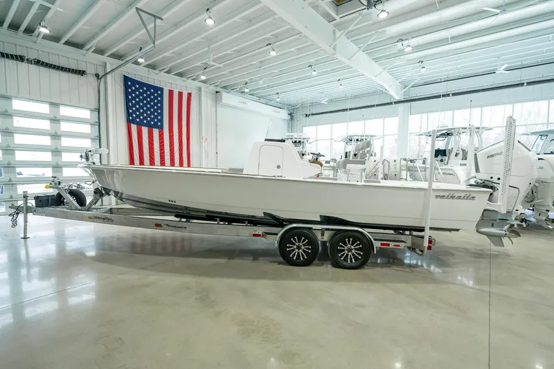 Slide: The Image of 2024 Valhalla Boatworks V-28 on trailer in showroom with American flag backdrop. - 2