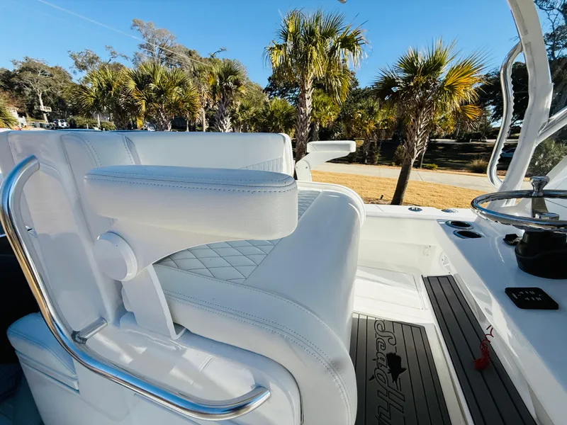 Slide: The Image of 2024 SeaHunter 28 Floridian boat interior with white seating and palm trees in the background. - 13