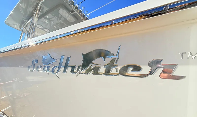 Slide: The Image of 2024 SeaHunter 28 Floridian boat logo on side hull, under clear blue sky. - 32
