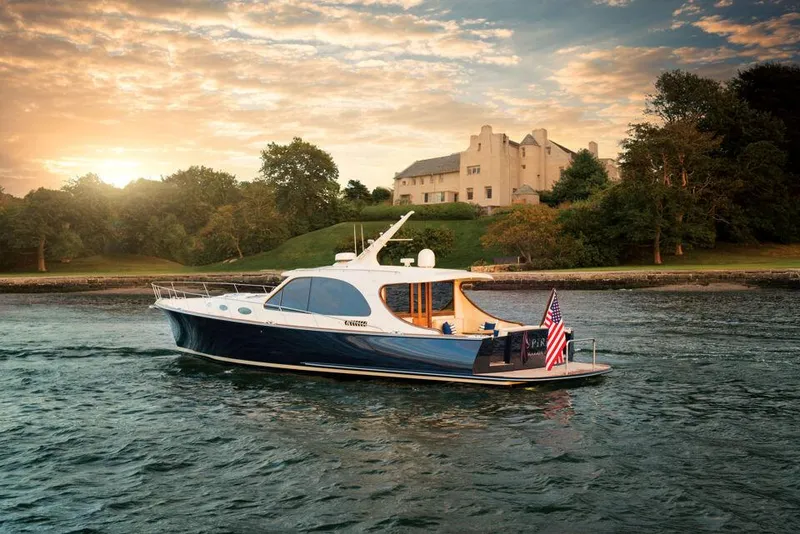 The Image of 2026 Palm Beach Motor Yachts PB55 cruising near a scenic shoreline at sunset. - 0
