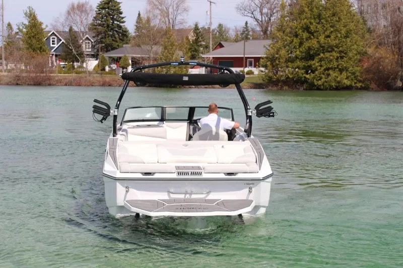 Slide: The Image of 2025 Supreme S220 boat cruising on a clear lake near a residential area. - 2