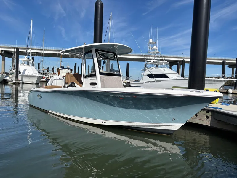 Slide: The Image of 2022 Sea Hunt Ultra 255 SE boat docked in marina, clear sky background. - 1