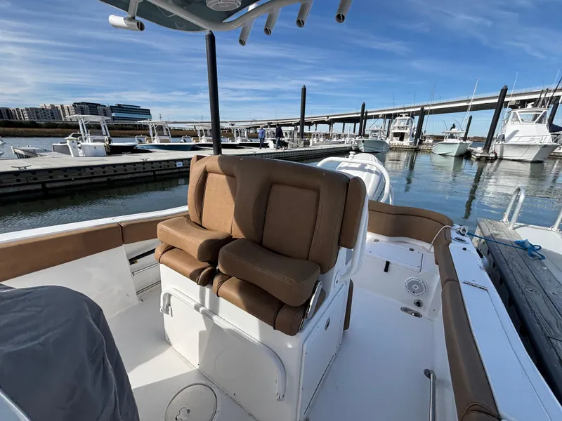 Slide: The Image of 2022 Sea Hunt Ultra 255 SE boat interior at marina, featuring tan seating and clear skies. - 4