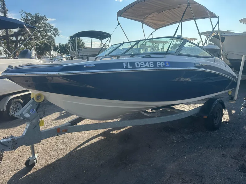 Slide: The Image of 2013 Yamaha SX192 boat on trailer, blue and white exterior, parked outdoors. - 2