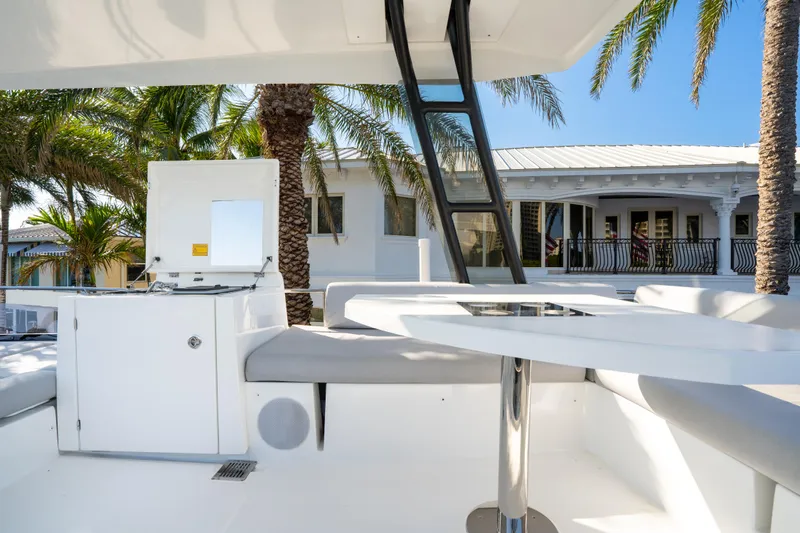 Slide: The Image of Prestige 460 Fly 2023 yacht deck with seating, palm trees, and a house in the background. - 12