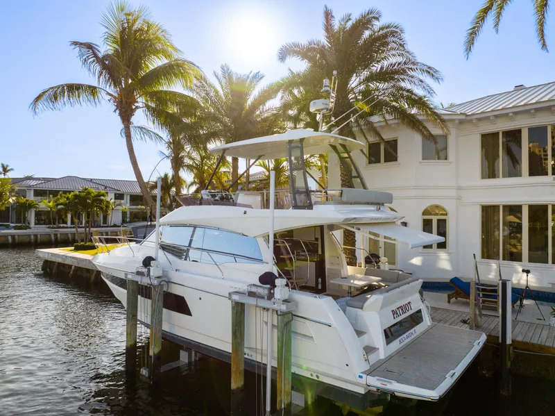 Slide: The Image of 2023 Prestige 460 Fly yacht docked by waterfront home with palm trees. - 2