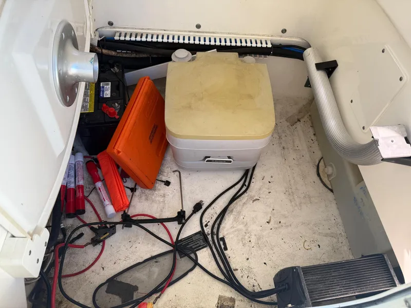 Slide: The Image of 2014 Boston Whaler 240 Dauntless storage compartment with battery, wires, and portable toilet. - 13