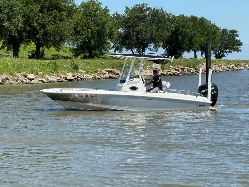 Slide: The Image of 2014 Boston Whaler 240 Dauntless boat cruising on a calm river near a grassy shoreline. - 16