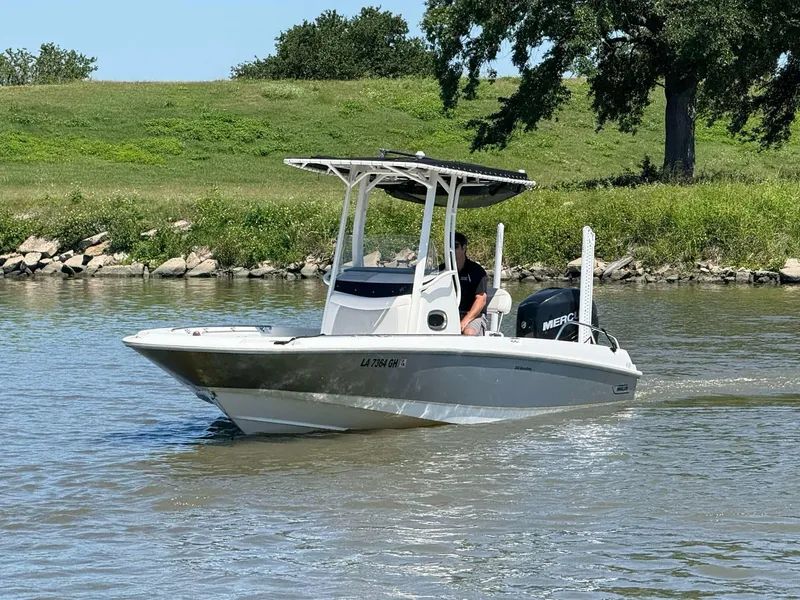Slide: The Image of 2014 Boston Whaler 240 Dauntless boat cruising on a calm river near grassy shoreline. - 17
