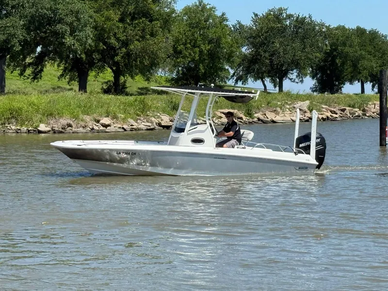 Slide: The Image of 2014 Boston Whaler 240 Dauntless boat cruising on a calm river with trees in the background. - 22