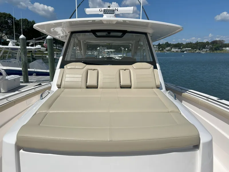 Slide: The Image of 2019 Pursuit S 408 Sport boat with beige seating, docked by a scenic waterfront. - 11