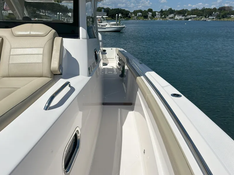 Slide: The Image of 2019 Pursuit S 408 Sport boat, beige seating, docked on calm water. - 13