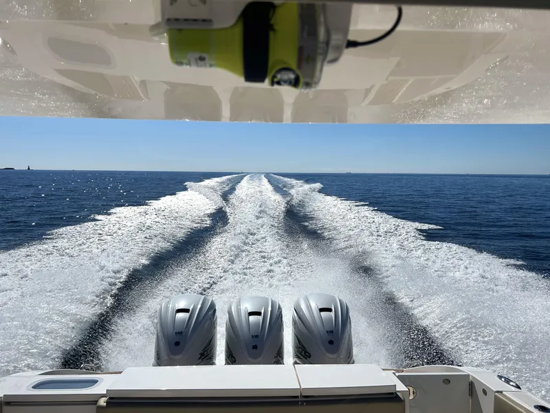 Slide: The Image of 2019 Pursuit S 408 Sport boat with triple engines cruising on open water. - 5