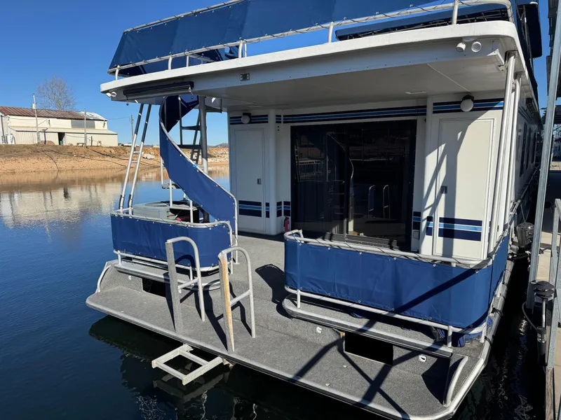 Slide: The Image of 1996 Stardust Cruisers 72x16 houseboat with blue accents docked on calm water. - 3