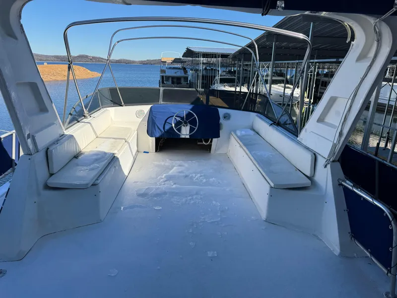 Slide: The Image of 1996 Stardust Cruisers 72x16 houseboat deck with seating and steering wheel, docked by the lake. - 7